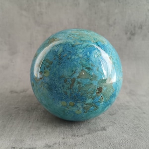 Op de afbeelding: Een gladde, ronde, blauwe en groene bol met een marmerpatroon.