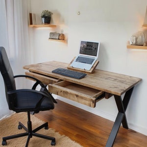 May include: A rustic wooden desk with black metal legs and a drawer. A laptop computer is on the desk with a keyboard and mouse. A black office chair is in front of the desk.