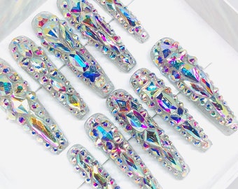 May include: Set of ten iridescent press-on nails with a variety of crystal designs.