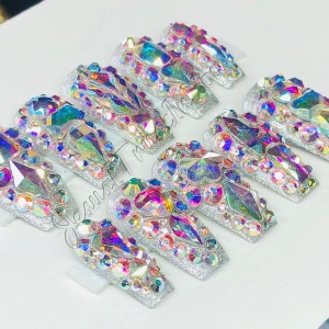 May include: Set of ten silver press-on nails with iridescent rhinestones and glitter.
