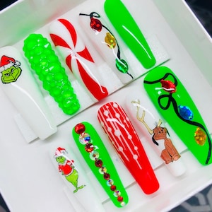 May include: Set of ten Christmas-themed false nails. The nails are long and feature a variety of designs, including candy canes, Christmas lights, a Grinch, and a reindeer. The nails are displayed on a white background.