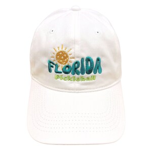 Pode incluir: Bon&eacute; de beisebol branco com um design bordado que apresenta um sol, uma bola de pickleball e o texto "Florida Pickleball".