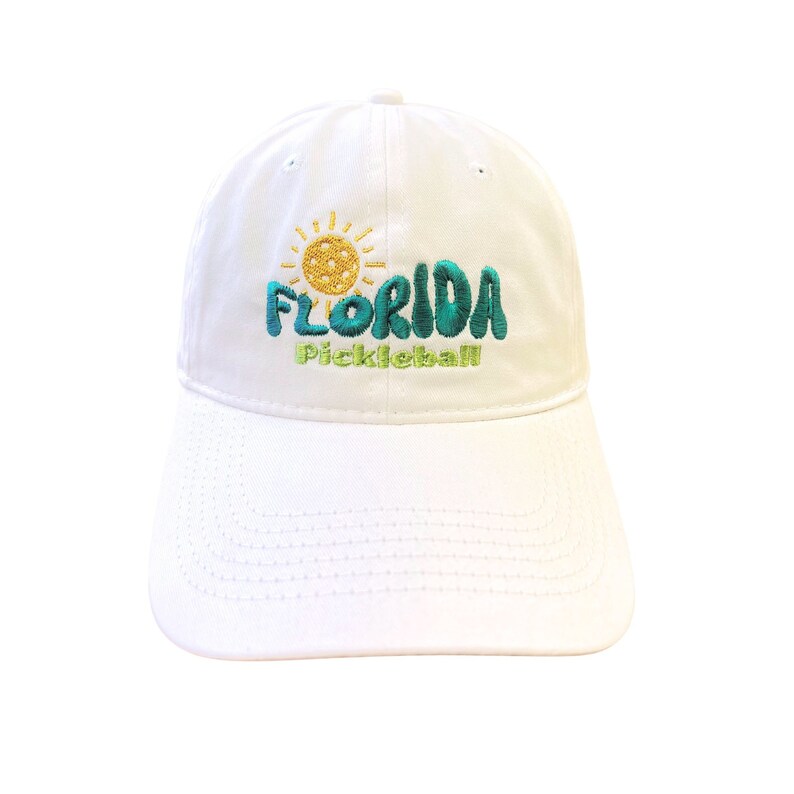 Pode incluir: Bon&eacute; de beisebol branco com um design bordado que apresenta um sol, uma bola de pickleball e o texto "FLORIDA Pickleball".
