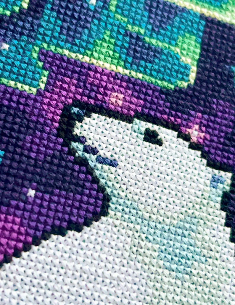 May include: Close-up of a cross-stitch pattern featuring a white polar bear with a purple and black background. The background has a pixelated design with a gradient of purple, black, and blue.