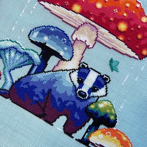 May include: A blue badger standing under a red and yellow mushroom with white spots. There are other blue mushrooms in the background.