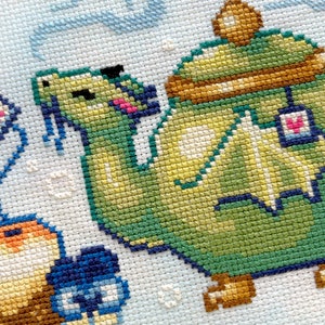 May include: A green teapot with a brown lid and a dragon design. The teapot is sitting on a white background with a blue and pink flower.