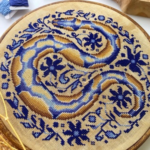Peut inclure: Un cercle de broderie circulaire avec un fond en tissu de lin beige. Le tissu est brod&eacute; d'un motif floral bleu et brun. Le cercle est en bois et a une finition naturelle.