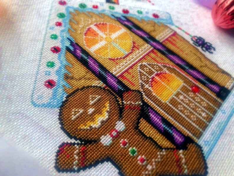 Closeup of Cookies & Scream gingerbread man. Details are clearly visible. Stitches are neat and tidy. Windows are fiery and have blood dropping down them. Candycanes are bright purple and black, and very shiny. Frosting is on the roof, with smarties