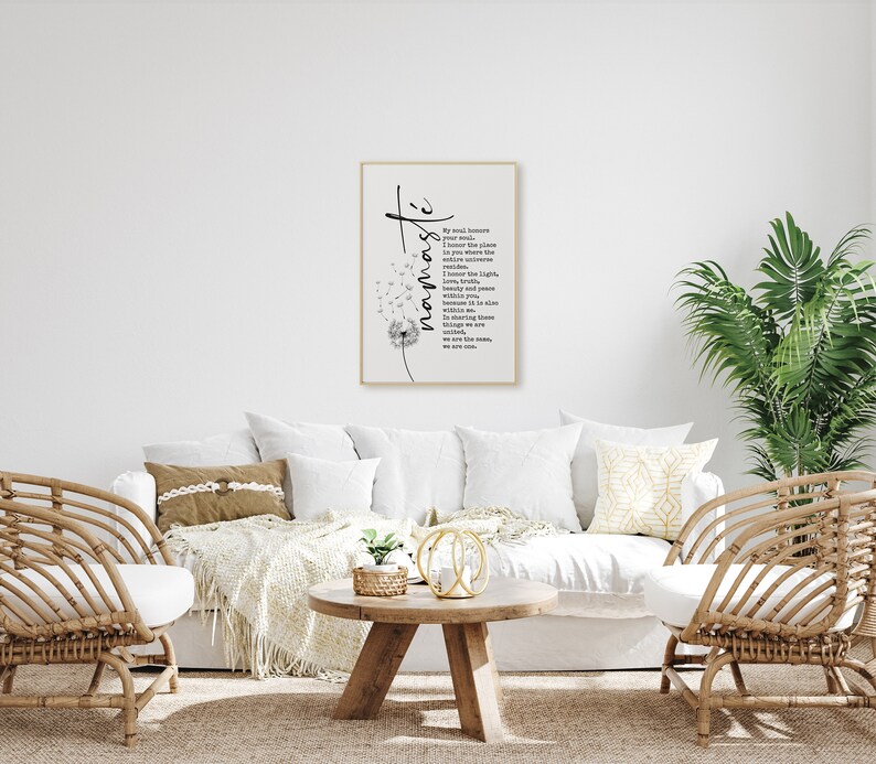 May include: A white couch with two chairs and a coffee table in a living room. A framed print with a dandelion and the word "namaste" is hanging on the wall. The print includes a poem about the soul and the universe.