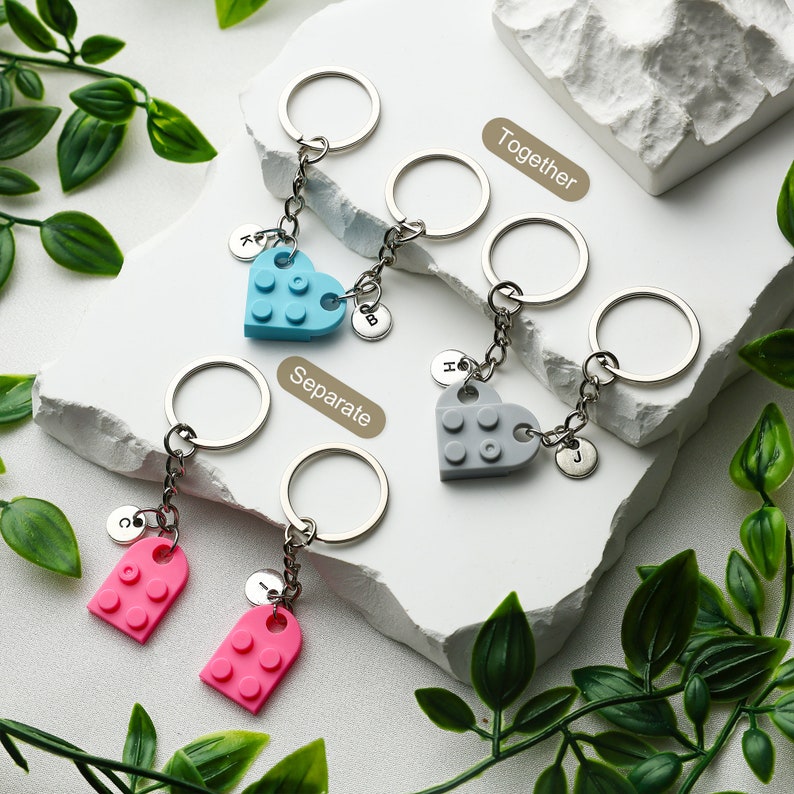 May include: Two sets of keychains with heart-shaped and rectangular charms. The charms are made to look like Lego bricks. One set is blue and gray, the other is pink. The keychains are labeled "Together" and "Separate".