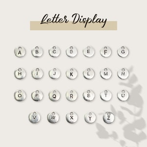 May include: A set of 26 silver letter charms, each with a different letter of the alphabet. The charms are arranged in alphabetical order.