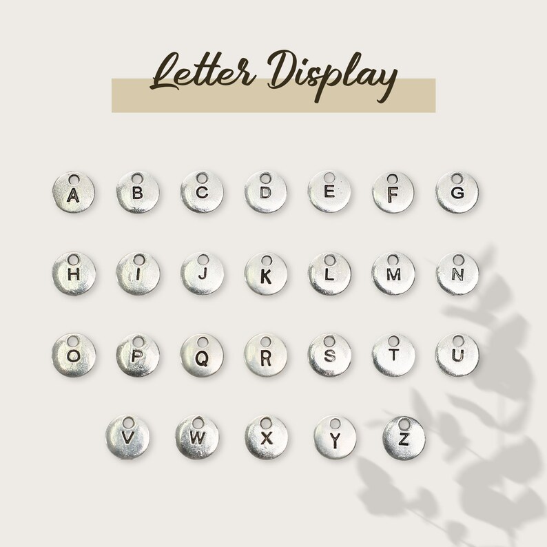 May include: A set of 26 silver letter charms, each with a different letter of the alphabet. The charms are arranged in alphabetical order.