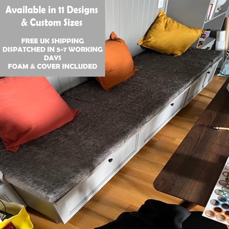 May include: A gray upholstered bench with three drawers and a white painted finish. The bench has three throw pillows, one orange, one red, and one yellow. The text on the wall reads "Available in 11 Designs & Custom Sizes FREE UK SHIPPING DISPATCHED IN 5-7 WORKING DAYS FOAM & COVER INCLUDED".