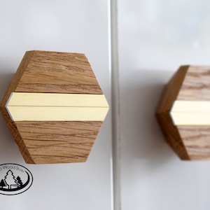 May include: Two hexagonal wooden cabinet knobs with a thin yellow stripe across the center. The knobs are made of light brown wood with a natural wood grain pattern. The text "Back to Wood Studio" is visible in the lower left corner of the image.