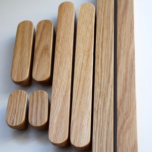 Pu&ograve; includere: Set di otto maniglie per cassetti in legno di diverse dimensioni. Le maniglie sono in legno marrone chiaro con finitura naturale. Le maniglie sono tutte di forma rettangolare con bordi arrotondati. Le maniglie sono disposte a scalare. Il testo "Back to Wood Studio" &egrave; visibile in un cerchio nella parte inferiore dell'immagine.