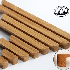 Op de afbeelding: Set van acht houten kastgrepen in verschillende maten. De grepen zijn gemaakt van lichtbruin hout en hebben een afgeronde, licht gebogen vorm. De grepen zijn in een verspringend patroon gerangschikt, met de grootste greep bovenaan en de kleinste greep onderaan. De grepen zijn allemaal gemaakt van hetzelfde type hout en hebben een gladde, gepolijste afwerking. De afbeelding toont ook een close-up van het uiteinde van een van de grepen, die de houtnerf en de manier waarop de greep in elkaar zit, laat zien.