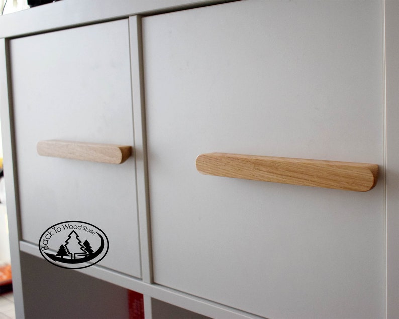 Pu&ograve; includere: Due maniglie per armadio in legno con bordi arrotondati, montate su ante di armadio bianche. Le maniglie sono in legno chiaro e sono lunghe circa 30 cm.