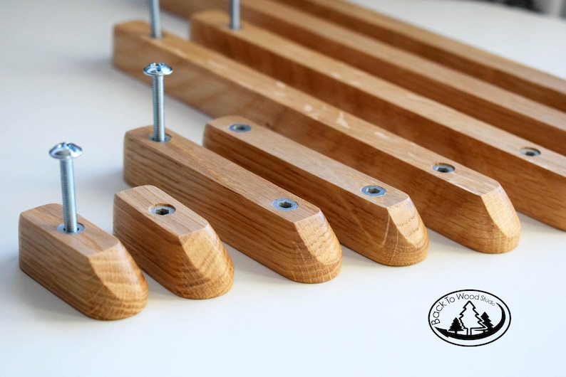 Pu&ograve; includere: Un set di sette maniglie per cassetti in legno con forma rettangolare arrotondata e una vite argentata al centro di ogni maniglia. Le maniglie sono disposte in fila dal pi&ugrave; grande al pi&ugrave; piccolo.