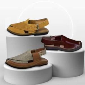 May include: Three pairs of open-toe sandals in different colors: tan suede, brown leather, and a tan and brown fabric combination. Each sandal has a strap around the ankle and a flat sole. The sandals are displayed on white pedestals.