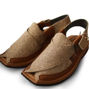 May include: A pair of brown and tan sandals with a woven fabric upper and leather accents. The sandals have a strap around the ankle and a buckle closure. The soles are brown and the overall design is casual and comfortable.