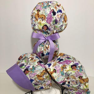 May include: Three purple and white patterned scrub hats with a purple ribbon on the top hat. The hats feature a watercolor design of women and animals.