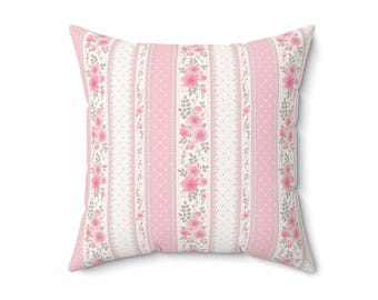 Puede incluir: Cojín decorativo cuadrado con un estampado floral rosa y blanco. El diseño presenta rayas verticales de rosas rosas, lunares blancos y bordes de encaje. Un acento suave y femenino para cualquier habitación.
