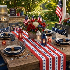 May include: A wooden table set for a 4th of July celebration, with a red, white, and blue star-spangled table runner. The table is decorated with plates, napkins, and lanterns, alongside American flags and floral arrangements.