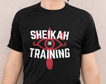 May include: A black t-shirt with a white graphic that says "Sheikah in Training" and a red stylized eye symbol.