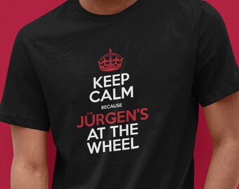 May include: Black t-shirt with a red graphic that says "Keep Calm Because Jürgen's At The Wheel" with a crown above the words "Keep Calm".