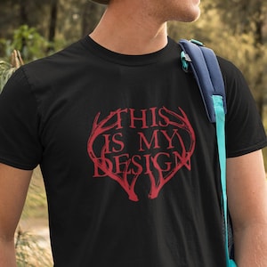 May include: A black t-shirt featuring a red graphic of antlers forming a heart shape with the text "This is my design" inside.