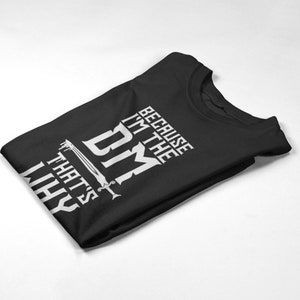 Puede incluir: Camiseta negra con texto blanco que dice "Because I'm the DM That's why". Se incluye un gr&aacute;fico de espada en el texto.