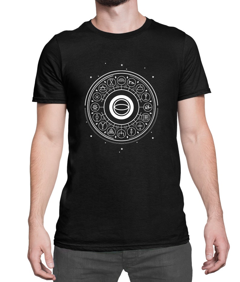 May include: A black t-shirt with a white graphic of a circle with various symbols and designs inside. The graphic is centered on the shirt.