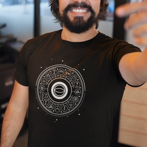 May include: A black t-shirt with a white graphic of a circle with symbols and a white ring in the center. The symbols include a sun, a moon, a mountain, a tree, a star, a wave, a lightning bolt, a heart, a hand, a flower, a bird, a fish, a snake, a spider, a skull, a cross, a triangle, a square, a circle, a line, a dot, and a spiral.