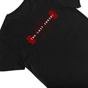 May include: Black t-shirt with the text "Bar Wars The Last Shredi" in red, featuring a barbell design. The shirt is made of a soft material and is suitable for workouts or casual wear.