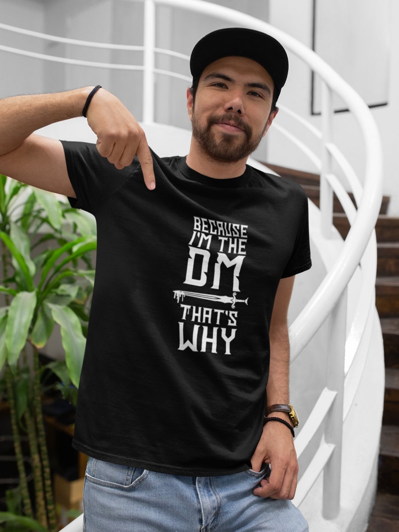 Puede incluir: Una camiseta negra con un gr&aacute;fico blanco que dice "Because I'm the DM That's Why" con un gr&aacute;fico de espada.