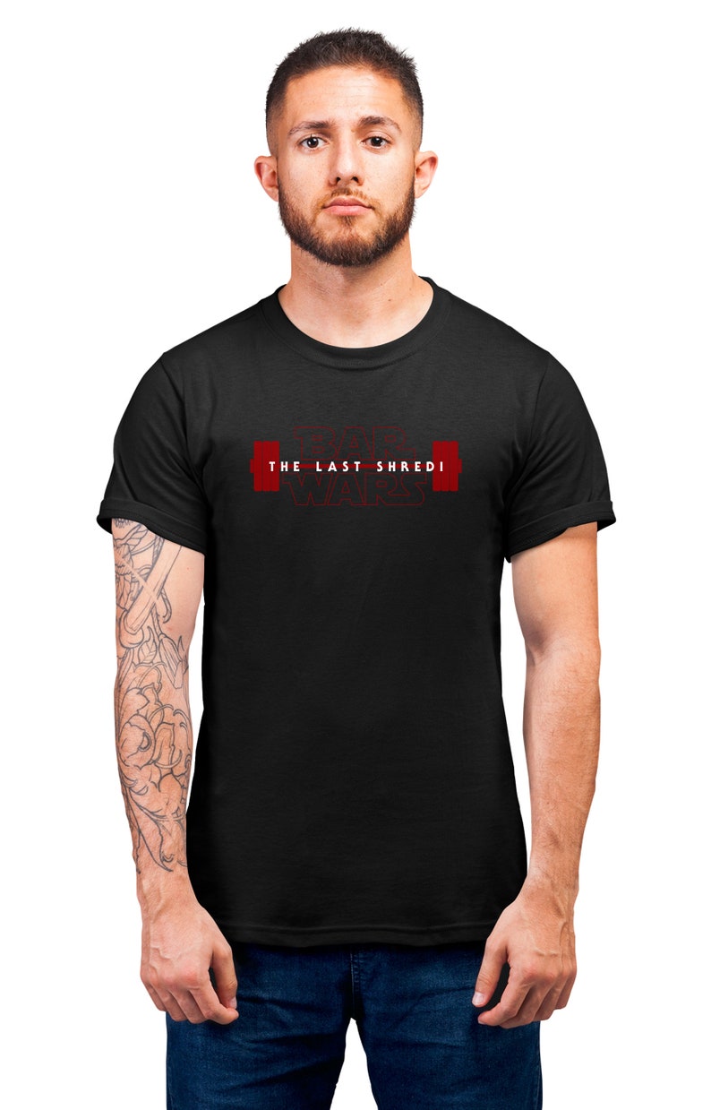 May include: Black t-shirt with the text "THE LAST SHREDI WARS" in red. The design features a barbell graphic. The shirt is a crew neck and short-sleeved.