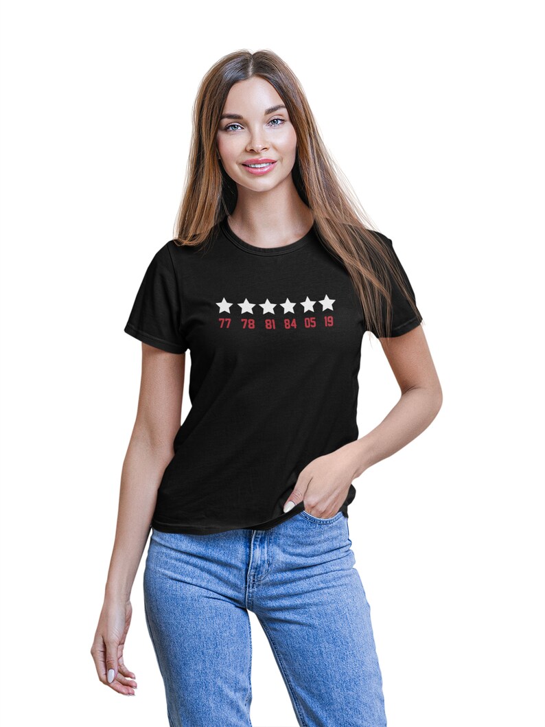 Pu&ograve; includere: Maglietta nera con cinque stelle bianche e i numeri 77 78 81 84 05 19 stampati in rosso sotto.