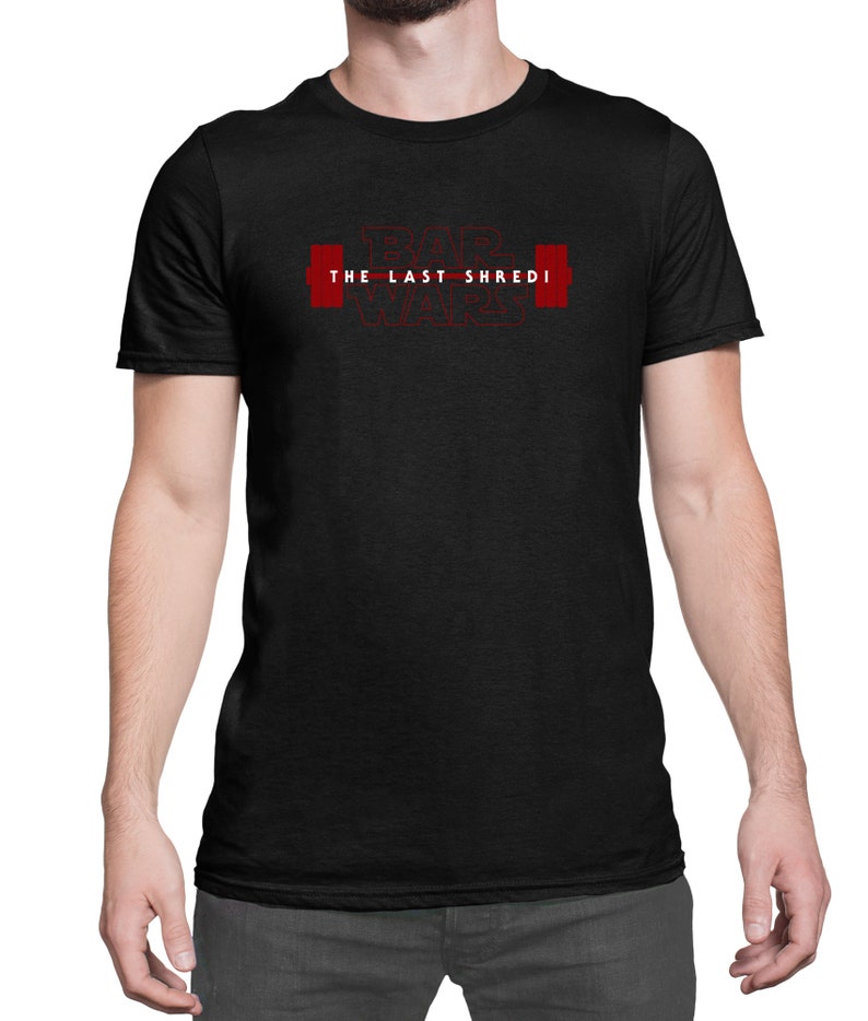 May include: Black t-shirt featuring the red text "BAR WARS THE LAST SHREDI" and a barbell graphic. The shirt is made of a soft material and has short sleeves.