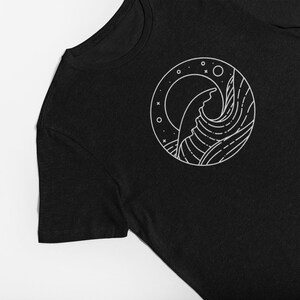 K&ouml;nnte beinhalten: Schwarzes T-Shirt mit einem wei&szlig;en Grafikdruck einer Welle und eines Mondes in einem Kreis.