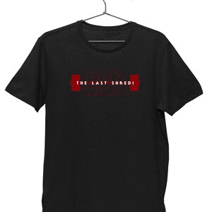 May include: Dark grey t-shirt featuring the red text "BAR WARS THE LAST SHREDI" and red barbell graphics. The t-shirt is suspended from a metal hanger.