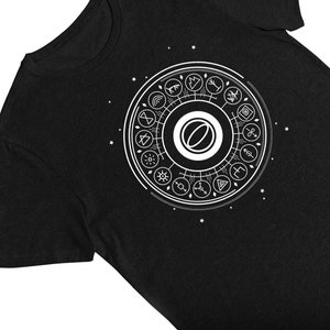 May include: Black t-shirt with a white graphic of a circle with symbols and a central eye.