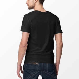 May include: A black crew neck t-shirt and dark blue denim jeans. The t-shirt is short-sleeved and the jeans have a zipper detail. The person is facing away from the camera.