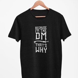Puede incluir: Camiseta negra con texto blanco que dice "Because I'm the DM That's Why" con un gr&aacute;fico de espada.