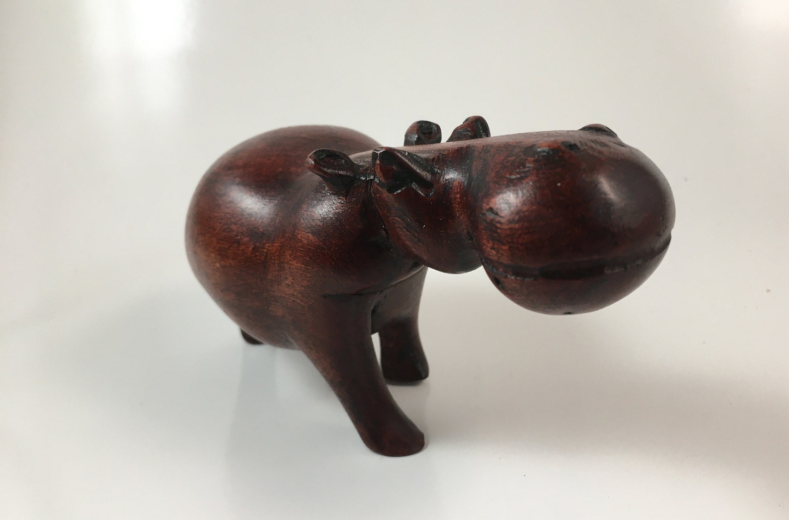 wooden figure carved into a hippo.  brown in color.