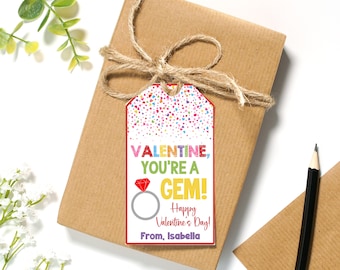 Könnte beinhalten: Ein farbenfroher Valentinstag-Geschenk-Anhänger mit einem Ring und einem roten Edelstein. Der Anhänger sagt "Valentine, You're a Gem! Happy Valentine's Day! From, Isabella."
