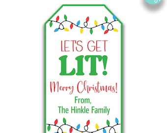May include: A white gift tag with a green border and a string of colorful Christmas lights. The text on the tag reads "Let's Get Lit! Merry Christmas! From, The Hinkle Family".