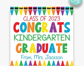 May include: A white printable sign with a colorful crayon border. The sign says "Class of 2023 Congrats Kindergarten Graduate" in colorful letters. The text "From, Mrs. Jackson" is at the bottom of the sign.
