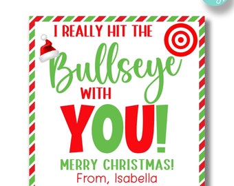 May include: A white gift tag with red and green striped border. The tag features a red and white Santa hat, a red target, and the text "I really hit the bullseye with YOU! Merry Christmas! From, Isabella".