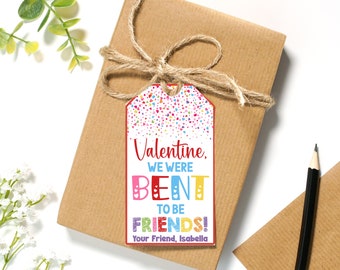 May include: A white Valentine's Day gift tag with a red border and colorful confetti. The tag says "Valentine, We Were Bent To Be Friends!" and "Your Friend, Isabella".