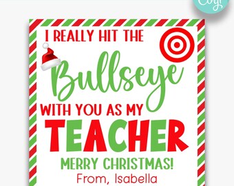 May include: A white printable gift tag with red and green striped border. The tag features a red and white Santa hat, a red target, and the text "I really hit the bullseye with you as my teacher. Merry Christmas! From, Isabella."
